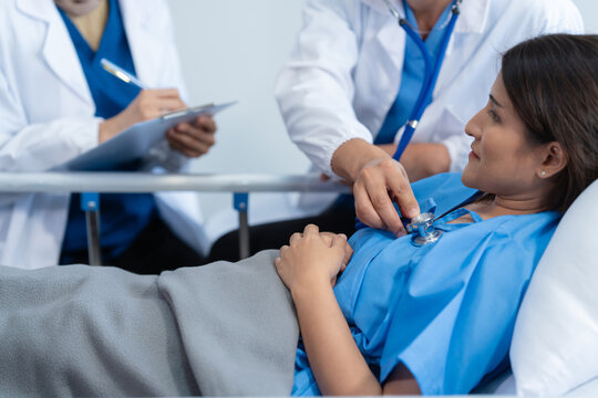 Two conficent doctor or specialist of kidney cancer talking together with female mix race patient on bed at medical ward, checkup, recovering after successful surgery concept.