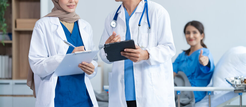 Two conficent doctor or specialist of kidney cancer talking together with female mix race patient on bed at medical ward, checkup, recovering after successful surgery concept.