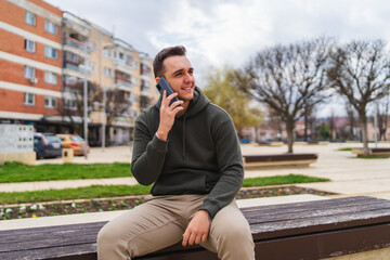 Obraz premium A man using and talking and taking selfie on his phone outside in the city during the day 
