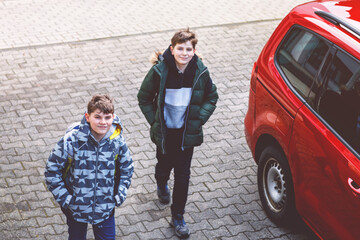 Two happy school students walking on street after school and chatting. Teenager boys, brothers and...