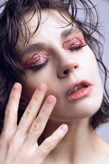 Close-up portrait of young beautiful girl with wet hair, red string makeup on eyelids. Revolutionary skincare treatment. Concept of modern beauty standards, plastic surgery, health, cosmetology