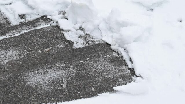 Close up of a man shoveling snow from driveway. Clearing snow in winter, snow removal with a shovel