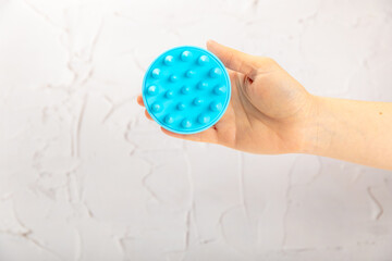 A brush for massaging the scalp in hands on a color background. Brush for hair growth stimulating brush. Hair massage. stimulating brush. Hair care, head relaxation concept. Copy space.