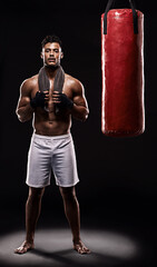 Fototapeta na wymiar Portrait, boxing bag and male boxer for break, studio and athlete on black background. Dark, training and combat sports or MMA for man model, workout, muscle and impact activity for martial arts