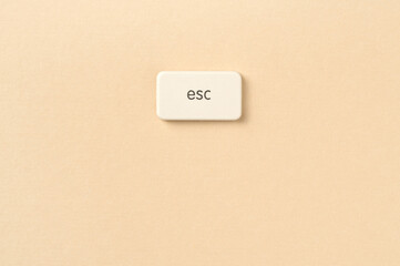 Close-up of an Escape symbol button on a beige background, symbolizing the idea of leaving...