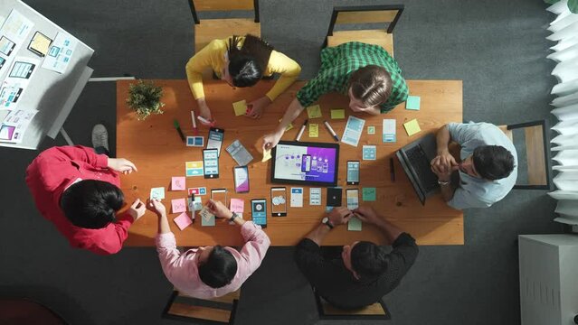 Top view of developer team working together to write idea about Ux ui design on colorful sticky note. Group of programmer looking at wireframe prototype at tablet and designing software. Convocation.