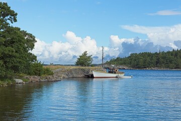 Old sailing boat moored to a pier on the island of Jussarö in summer with clouds in the sky, Raasepori, Finland.