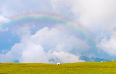 Beautiful nature of Kazakhstan on the Assy plateau. White yurt under the rain clouds and rainbow.