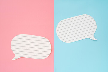 double white paper with line speech bubbles on pink and blue background, top view