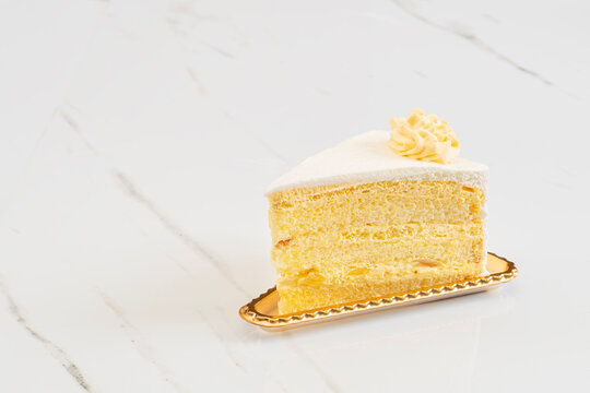 Layered mango cake on a golld  single serve plate with a marble background