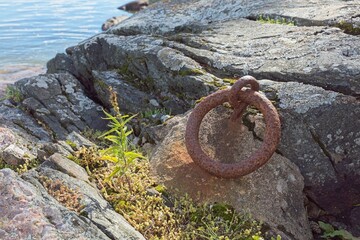 Old and rusty mooring ring fastened into a rock and used to tie up boats in summer.