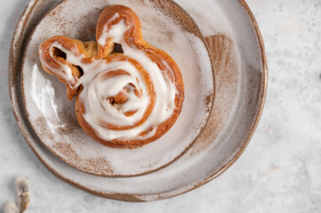Fresh homemade Cinnamon Rolls pastries covered in cream cheese icing for Easter. Easter festive food. Cinnamon roll bunny. Food for children.