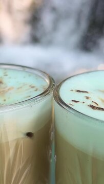 The zooming out of iced cappuccino with coffee beans and cookies. two glasses on the background of a waterfall High quality 4k footage