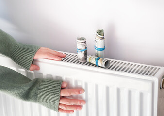 Central heating problem at home. Woman checking heating radiator in cold apartment