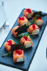 Rolls of red fish and cheese on the festive table.