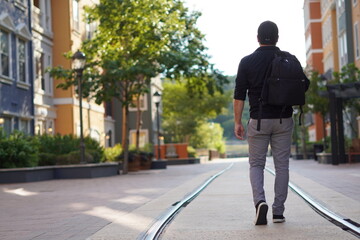 Fototapeta na wymiar a man in a backpack walks along the rails on a street