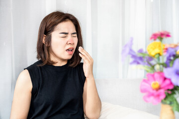 allergic Asian woman suffer from pollen allergy symptoms sneezing and has runny nose with bloom...