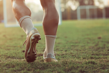 Closeup of soccer player walking on grass field. Legs of footballer playing competition match. Sports horiznotal background. Athlete in soccer cleats and soccer socks - obrazy, fototapety, plakaty