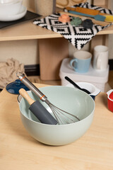 Dough kneading bowl with rolling pin and whisk on kitchen table.