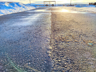 Sunlight Reflecting on a Wet Asphalt Road. Sun peeks over a ice covered road, casting a glow on the...