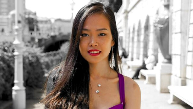 Petite Asian woman smiling and winking, being secretive and seductive. Close up slow motion shot. Vienna, Austria.