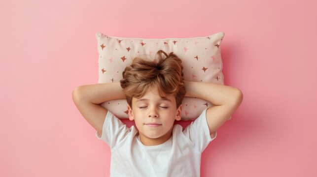 a young man sleeping on pillow isolated on pastel pink colored background. boy sleep deeply peacefully rest. Top above high angle view photo portrait of satisfied . child wear white shirt