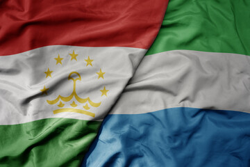 big waving national colorful flag of sierra leone and national flag of tajikistan.