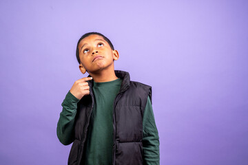 young hispanic boy wearing black vest and green shirt is looking up at the camera