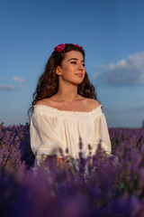 Fototapeta na wymiar Beautiful young woman with long curly hair posing in the field of lavender. Warm colors.