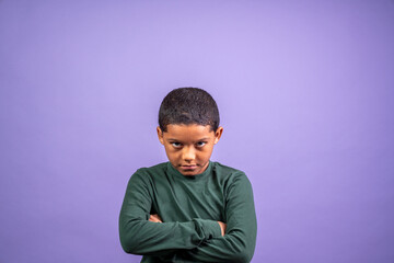 A young boy is standing with his arms crossed and looking down