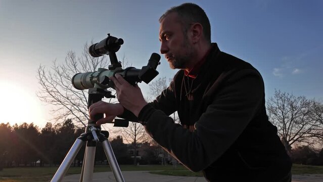 Amateur astronomer observing Sun eclipse and Sun with a telescope and special solar filter.	