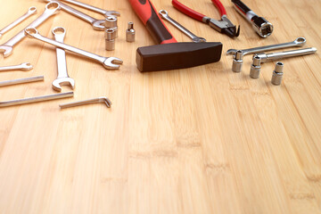 A set of working tools, a hammer, a screwdriver, sockets for repair on a bamboo, wooden background. Top view