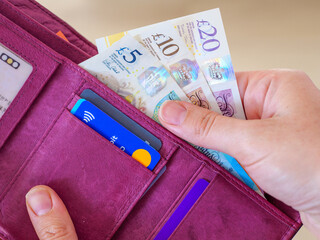 Close up of hand taking out British UK pound notes in cash as spending money to pay from wallet