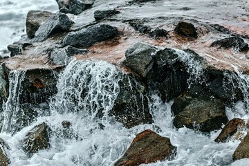 Naklejka premium water flowing over rocks
