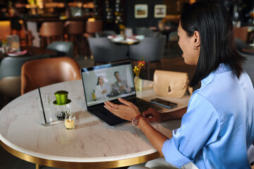 Businesswoman sitting at cafe table when video calling her team