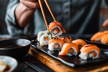 Fotobehang A person eating sushi with chopsticks. Seafood. Closeup macro shot. © abvbakarrr