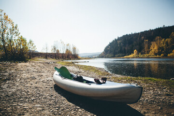 A white kayak rests on the lake shore under the sky