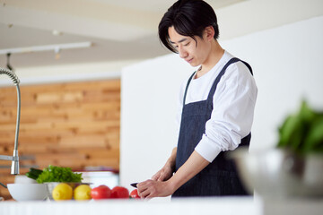 キッチンで料理を作る若い日本人の男性
