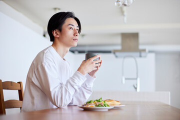Obraz na płótnie Canvas リビングにて朝食を食べる若い日本人の男性