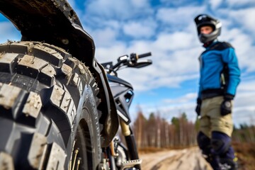 Obraz premium rider standing next to a bike, focus on dual sport tire tread