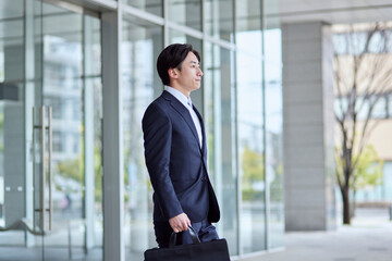 Fototapeta premium オフィスビルとスーツを着た若い日本人ビジネスマン