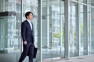 オフィスビルとスーツを着た若い日本人ビジネスマン - obrazy, fototapety, plakaty
