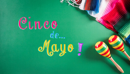 Cinco de Mayo holiday background made from maracas, mexican blanket stripes or poncho serape on green background.