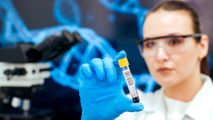 A female laboratory assistant conducts an experiment in a scientific laboratory, studying a blood...