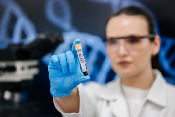 Laboratory assistant conducts an experiment in a scientific laboratory, studying a blood sample in...