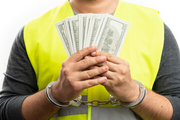 Close-up of arrested constructor in handcuffs holding cash money