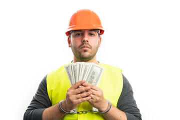 Corrupted builder man in handcuffs holding stolen money