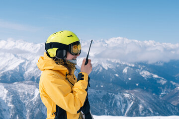 Female snowboarder using walkie-talkie in high mountains, extreme winter sport outdoor