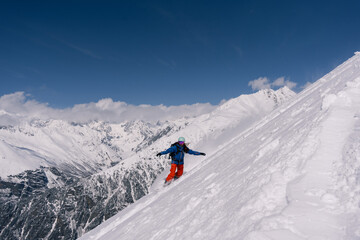 Naklejka na ściany i meble female snowboarder riding on slope of powdery snow in high mountains. Freeride at ski resort, amazing mountain peaks skyline