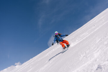 Naklejka na ściany i meble female snowboarder riding on slope of powdery snow in high mountains. Freeride at ski resort, amazing mountain peaks skyline